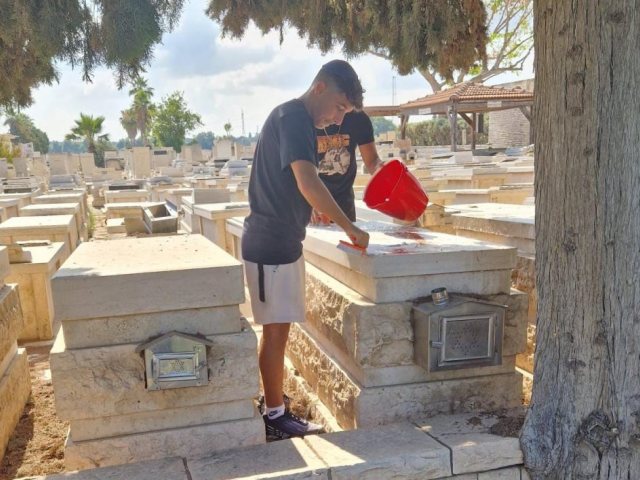 חבריו של יאיר מנקים את המצבות בבית העלמין. א' מיכאלי