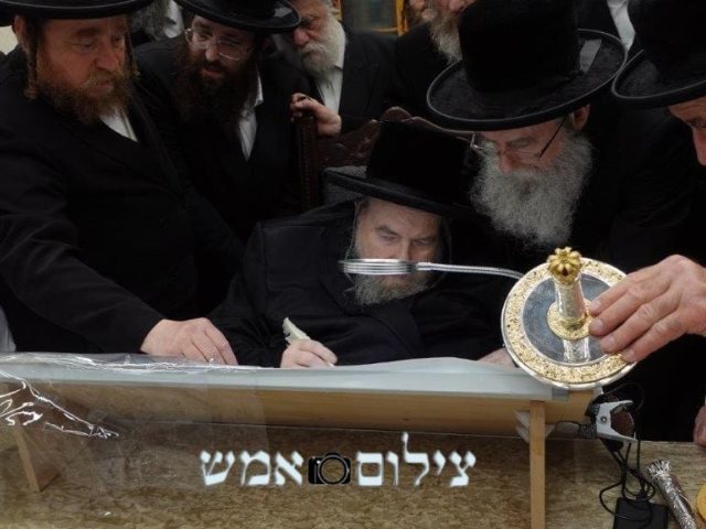 האדמור מבעלזא שליטא כותב אות בספר התורה. צילום אמ"ש