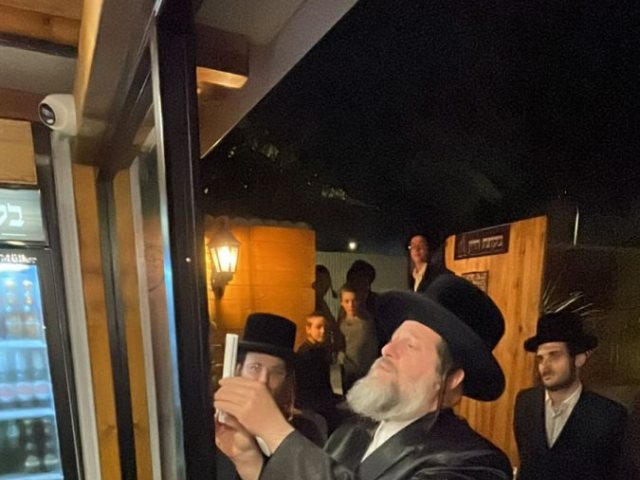 האדמור משאץ בקביעת מזוזה בפתח החנות. צילום: יחצ